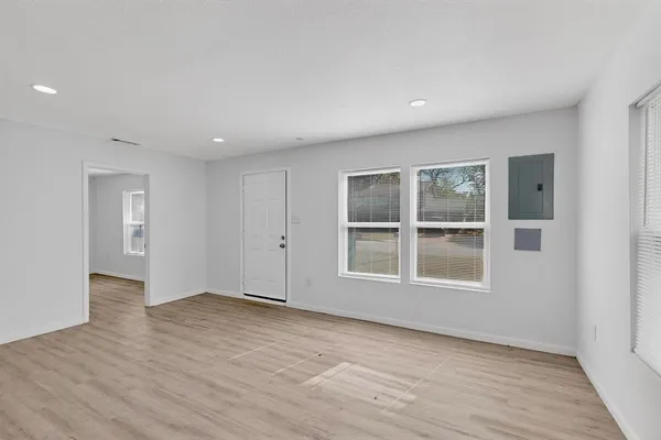 an empty room with wooden floor and windows