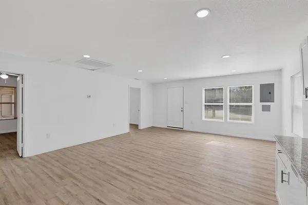 a view of an empty room with wooden floor and a window