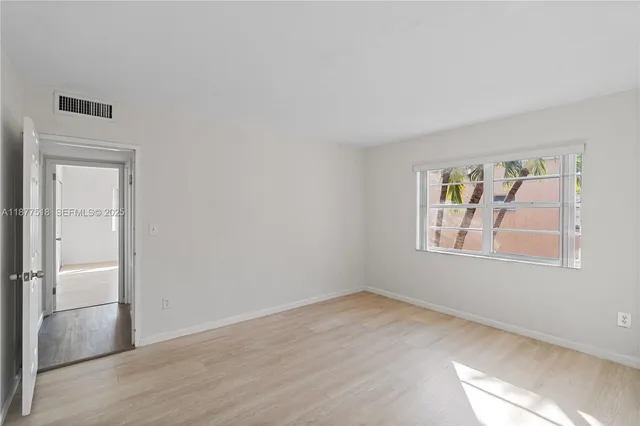 a view of empty room with window and wooden floor