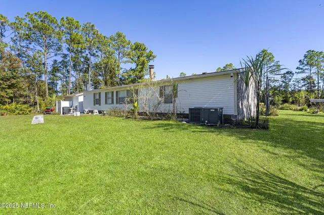 a view of a house with a big yard and large trees