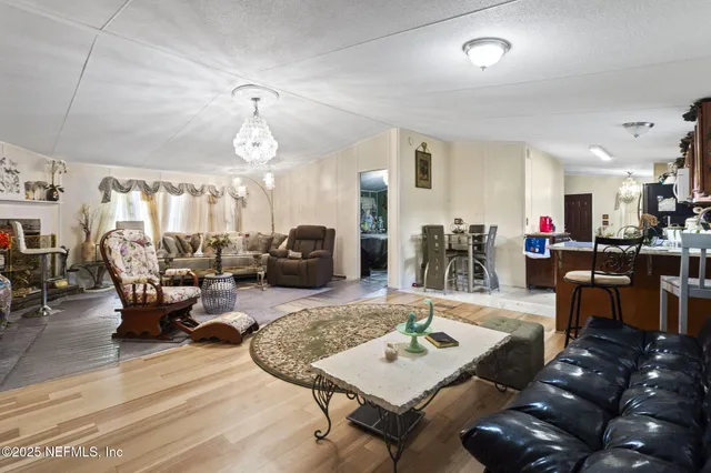 a living room with furniture kitchen view and a wooden floor