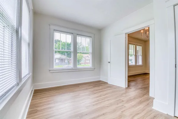 a view of an empty room with wooden floor and a window