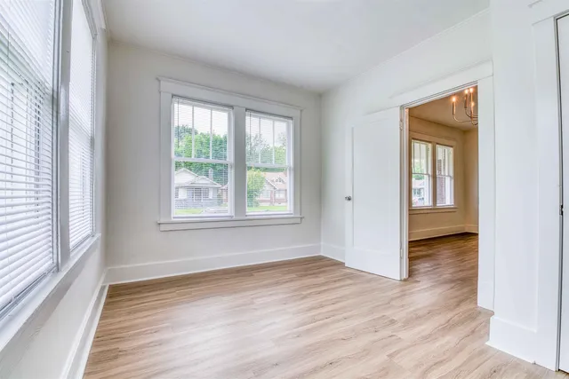 a view of an empty room with wooden floor and a window