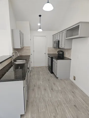 a kitchen with granite countertop a sink stainless steel appliances and cabinets