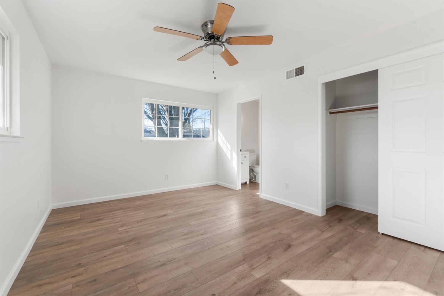 1713 Wolverine Way Modesto, CA 95355 - Photo 14 of 28 an empty room with wooden floor ceiling fan and windows