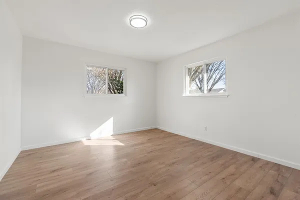 an empty room with wooden floor and window