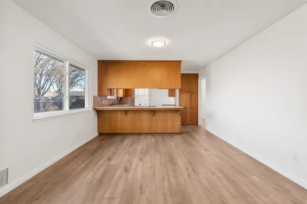 a view of an empty room with a window and wooden floor
