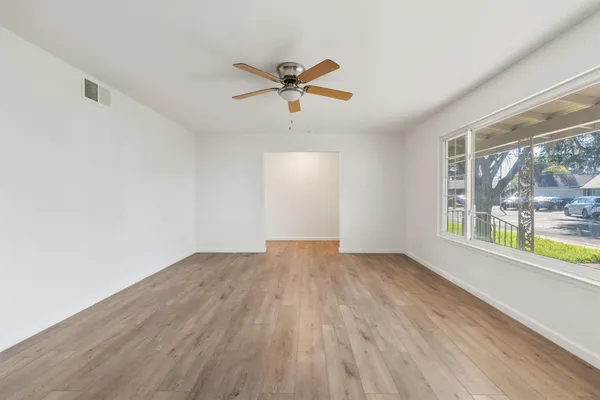 a view of empty room with wooden floor and fan