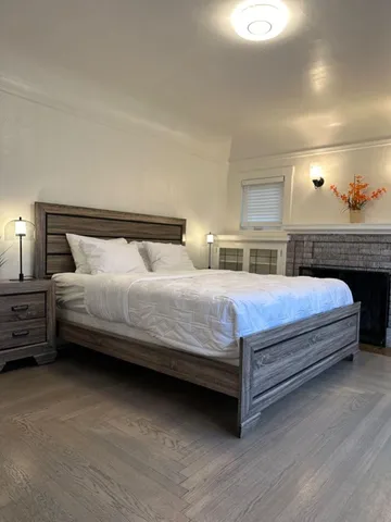 a bedroom with a bed and a dresser with wooden floor