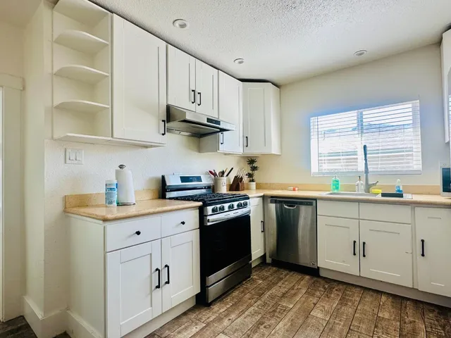 a kitchen with stainless steel appliances granite countertop a sink and cabinets with wooden floor