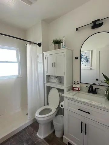 a bathroom with a granite countertop toilet sink and mirror
