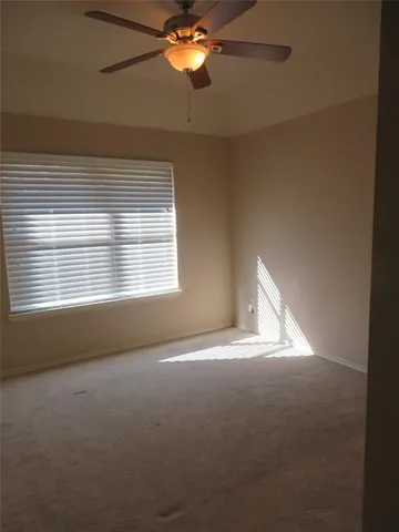 a view of empty room with window and chandelier fan