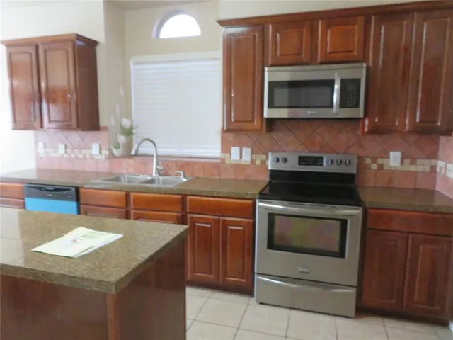 a kitchen with granite countertop stainless steel appliances a stove sink and microwave