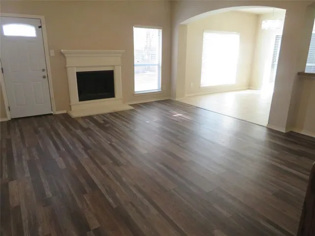 an empty room with wooden floor fireplace and windows