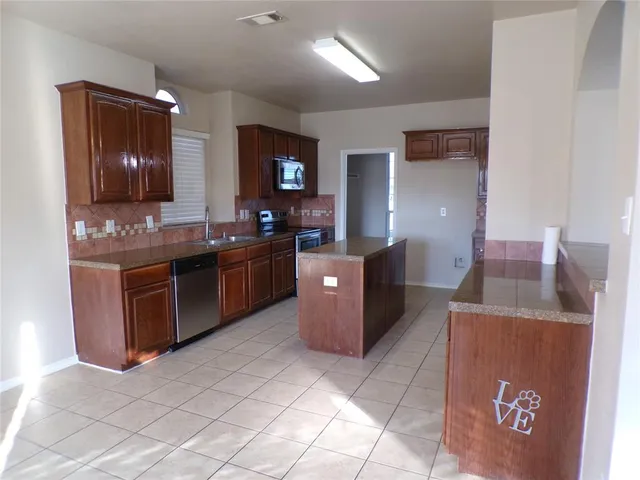 a kitchen with a stove a sink a counter top space and cabinets