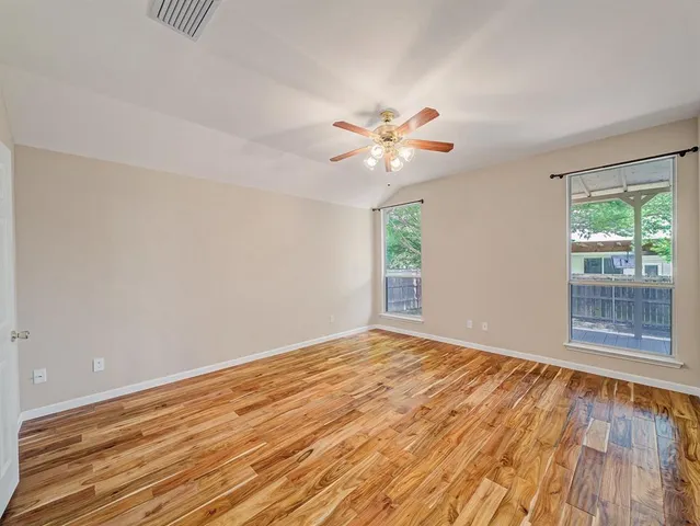 a view of an empty room with a window and wooden floor