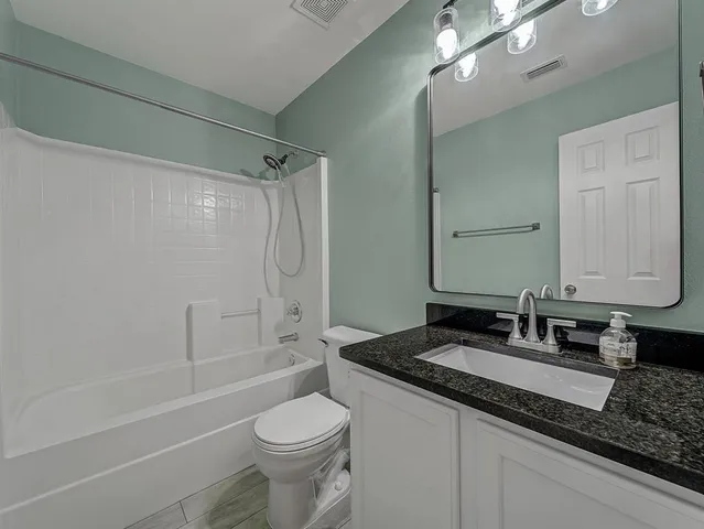 a bathroom with a granite countertop sink toilet and shower