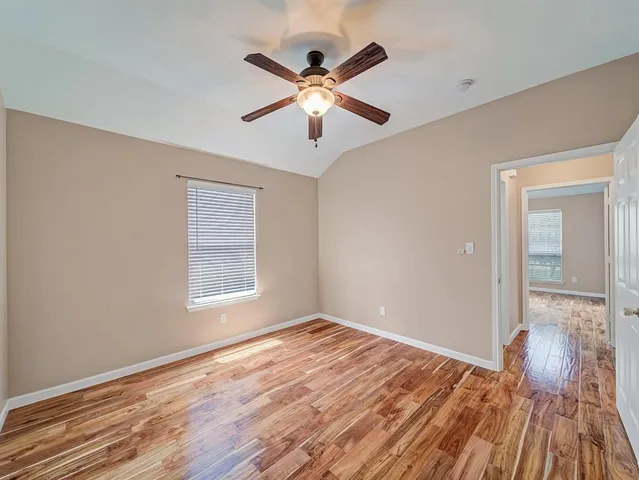 a view of empty room with wooden floor and fan