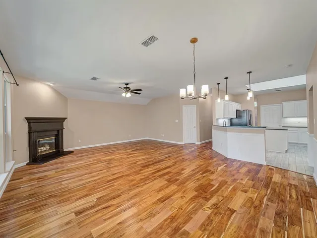 a view of a kitchen with kitchen island a sink wooden floor and a fireplace