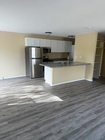 a kitchen with stainless steel appliances wooden floor and a refrigerator
