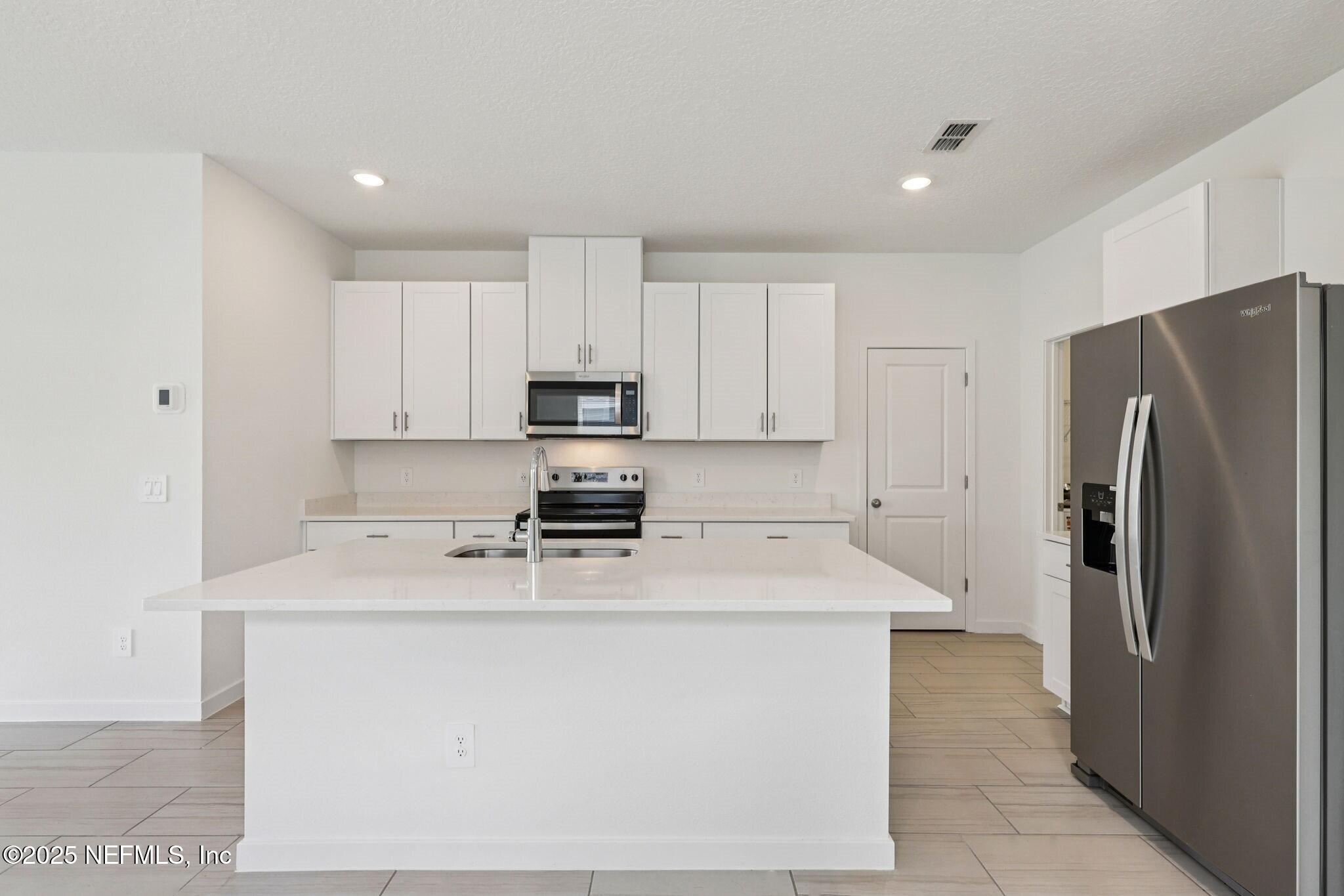 a kitchen with stainless steel appliances a refrigerator sink and white cabinets