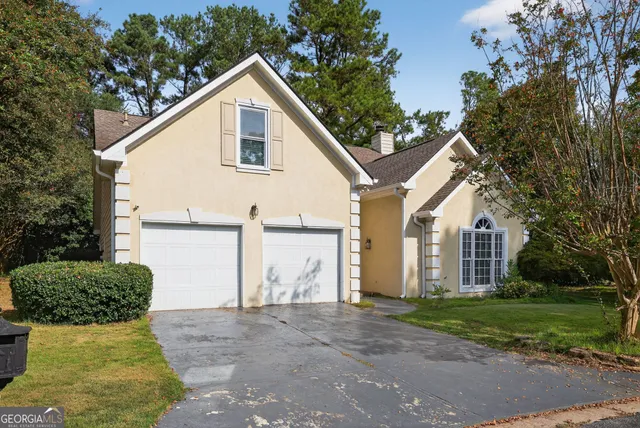 a view of a white house next to a yard and large trees