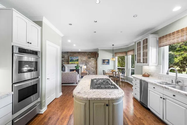 a kitchen with stainless steel appliances granite countertop a stove top oven a refrigerator a sink and dishwasher with wooden floor