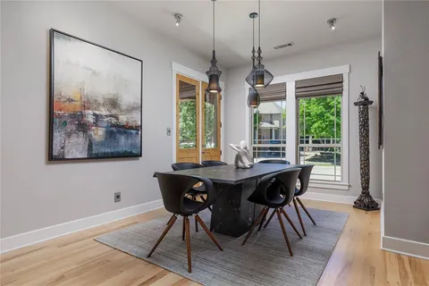a dining room with wooden floor a chandelier a wooden table and chairs
