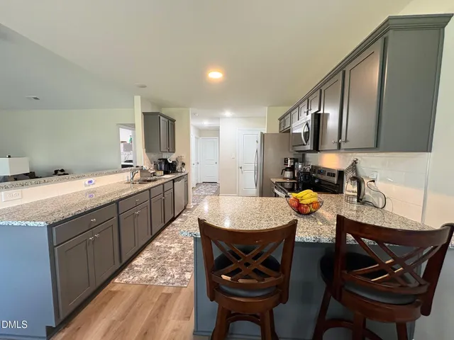 a kitchen with a sink chairs and a refrigerator