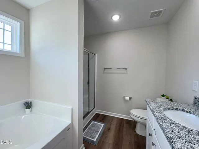 a bathroom with a granite countertop sink a toilet and shower