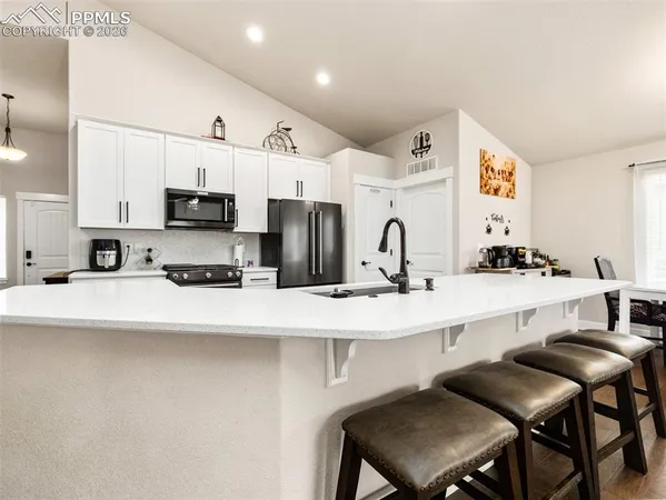 a kitchen with stainless steel appliances a stove a sink a microwave a refrigerator a white table and chairs