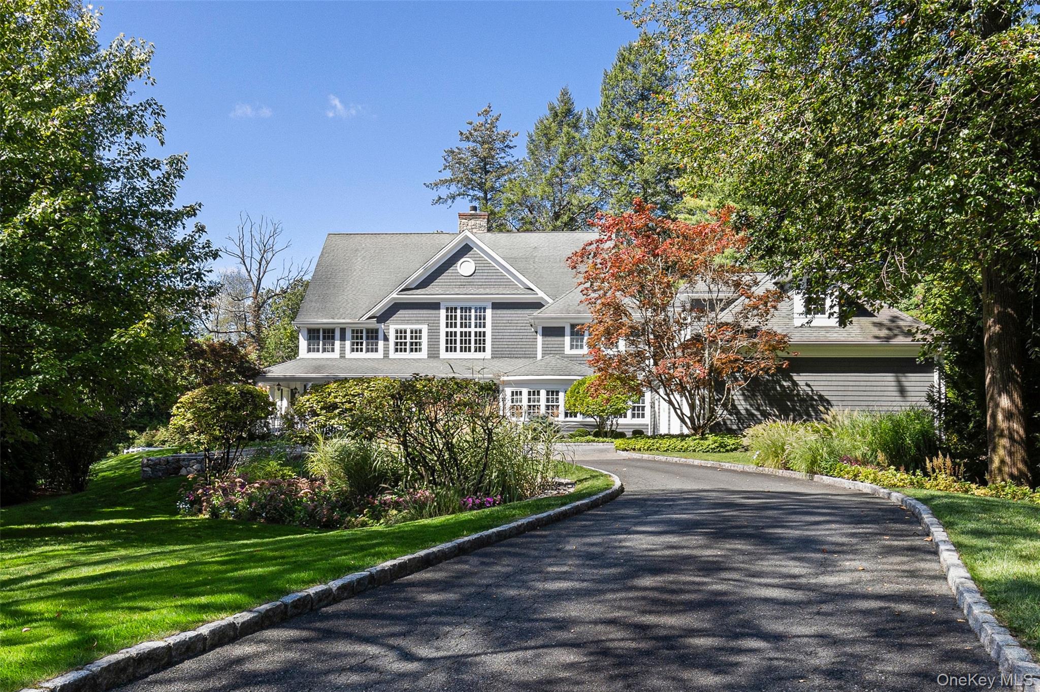 Shingle-style home featuring a front lawn, a chimney, and asphalt driveway