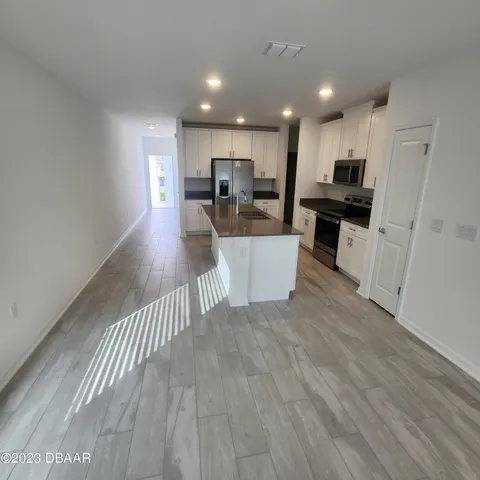 a view of a kitchen with kitchen island wooden floor center island and stainless steel appliances