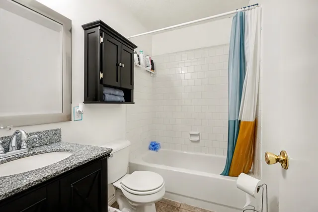 a bathroom with a granite countertop sink toilet and shower