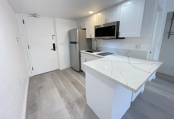 a kitchen with stainless steel appliances white cabinets a sink a stove a refrigerator and a microwave