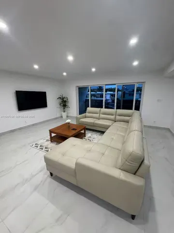 a living room with stainless steel appliances furniture and a flat screen tv