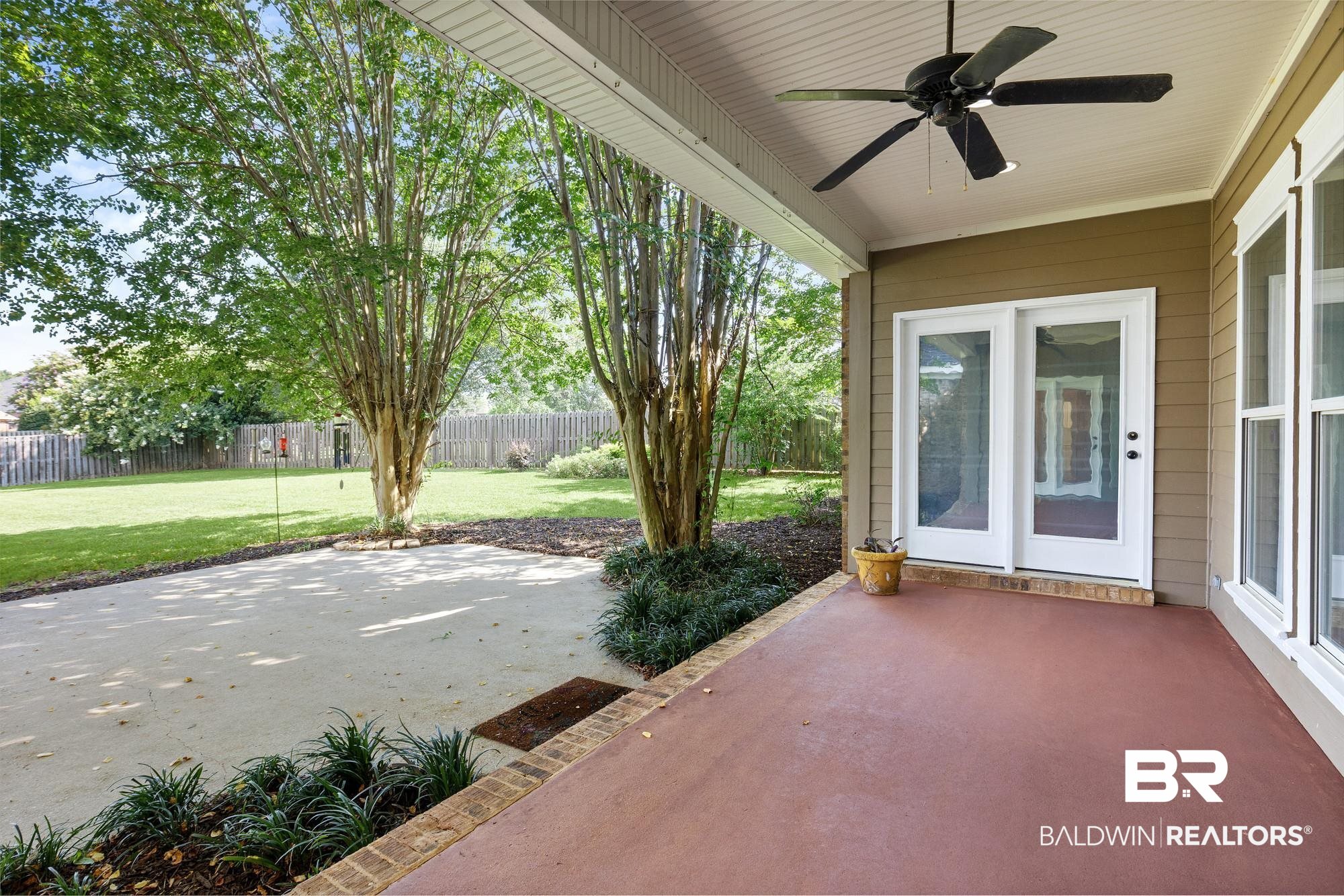 11261 Halcyon Loop Daphne, AL 36526 - Photo 30 of 41 Expansive covered patio featuring a ceiling fan, direct access via double glass doors, a large concrete pad, mature trees, and a spacious green lawn