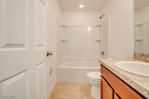 a bathroom with a granite countertop sink a toilet a mirror and bathtub