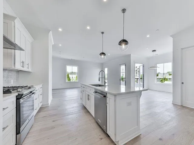 a large kitchen with stainless steel appliances granite countertop a lot of counter space and wooden floor