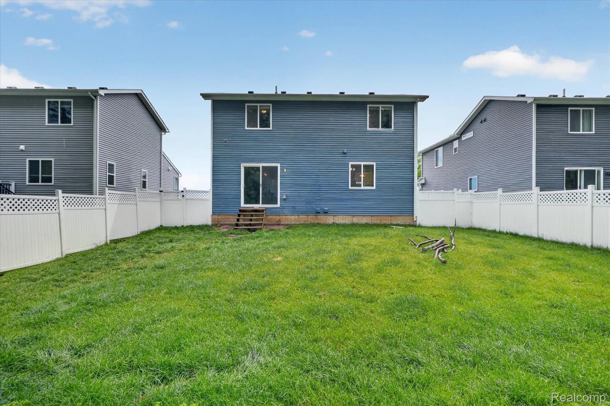5382 Rural Terrace Waterford, MI 48329 - Photo 32 of 35 Expansive backyard featuring a manicured lawn, a full vinyl privacy fence, and a two-story residence with blue siding