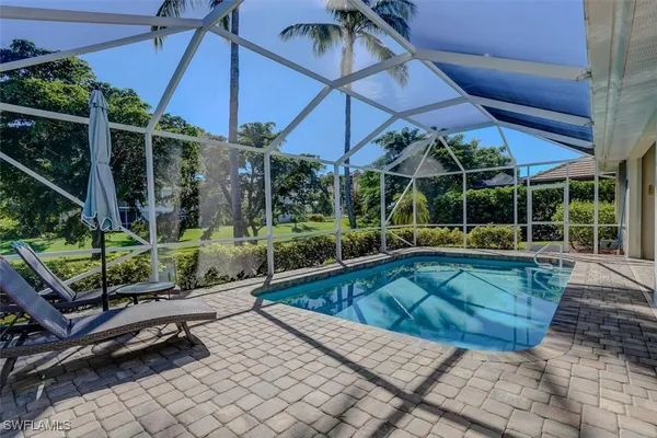 a view of a backyard with swimming pool and sitting area