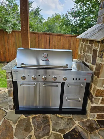 a view of barbeque grill with granite countertop a sink and a wooden fence
