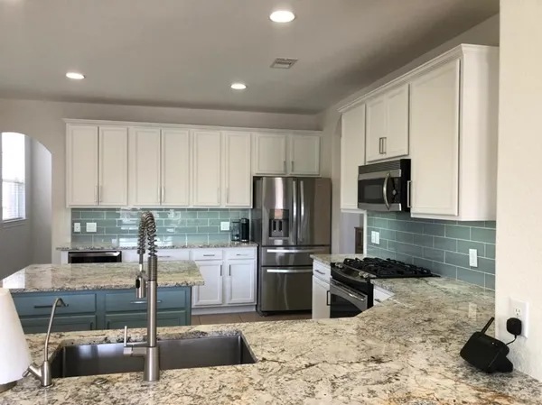 a kitchen with kitchen island granite countertop a sink a counter top space appliances and cabinets