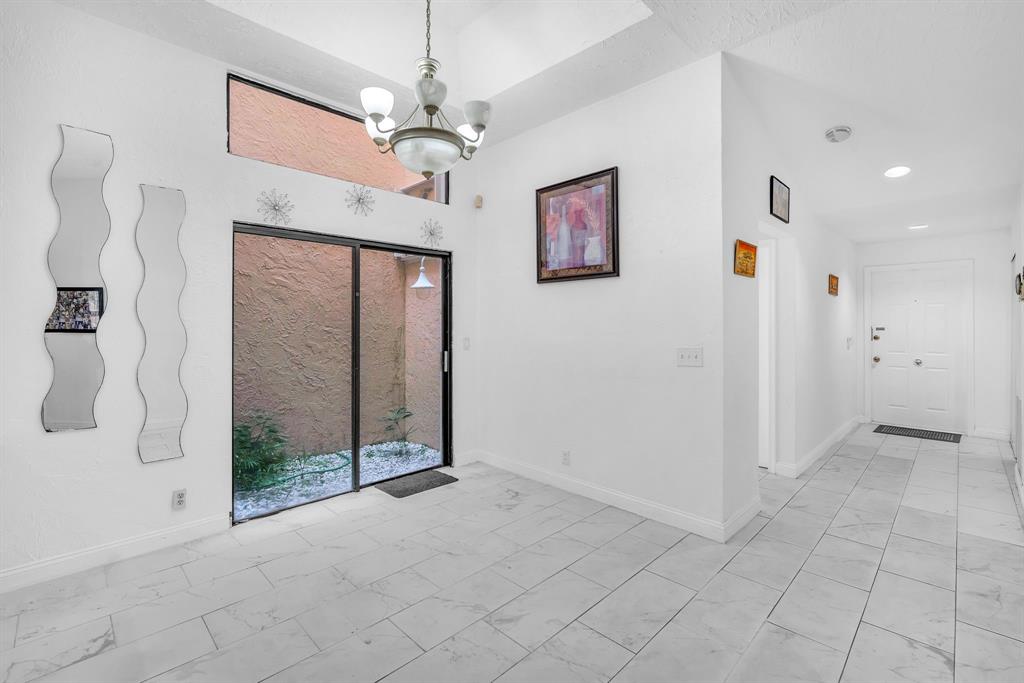 22710 Meridiana Drive Boca Raton, FL 33433 - Photo 14 of 39 a view of a hallway with chandelier fan and glass door