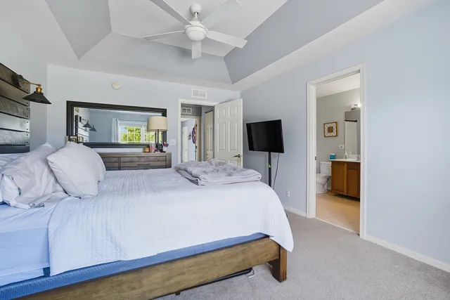 a bedroom with a large bed a flat tv screen and a ceiling fan