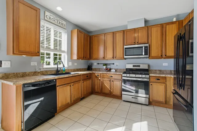 a kitchen with stainless steel appliances granite countertop a stove top oven a sink dishwasher and a microwave oven with cabinets