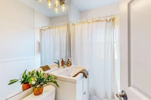 a bathroom with a sink a mirror and a shower curtain