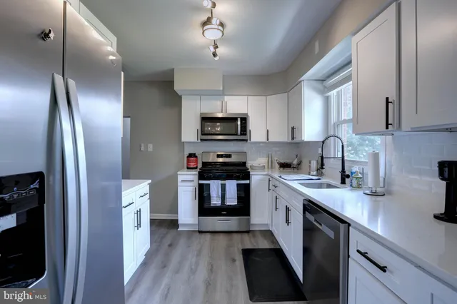 a kitchen with stainless steel appliances granite countertop a refrigerator a stove top oven a sink and dishwasher