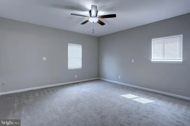 an empty room with windows and ceiling fan