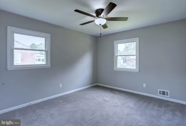 an empty room with a window and a fan